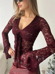 Woman wearing a burgundy lace dress with long sleeves against a white background