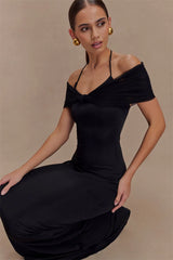 Woman wearing a black off-shoulder dress against a beige background