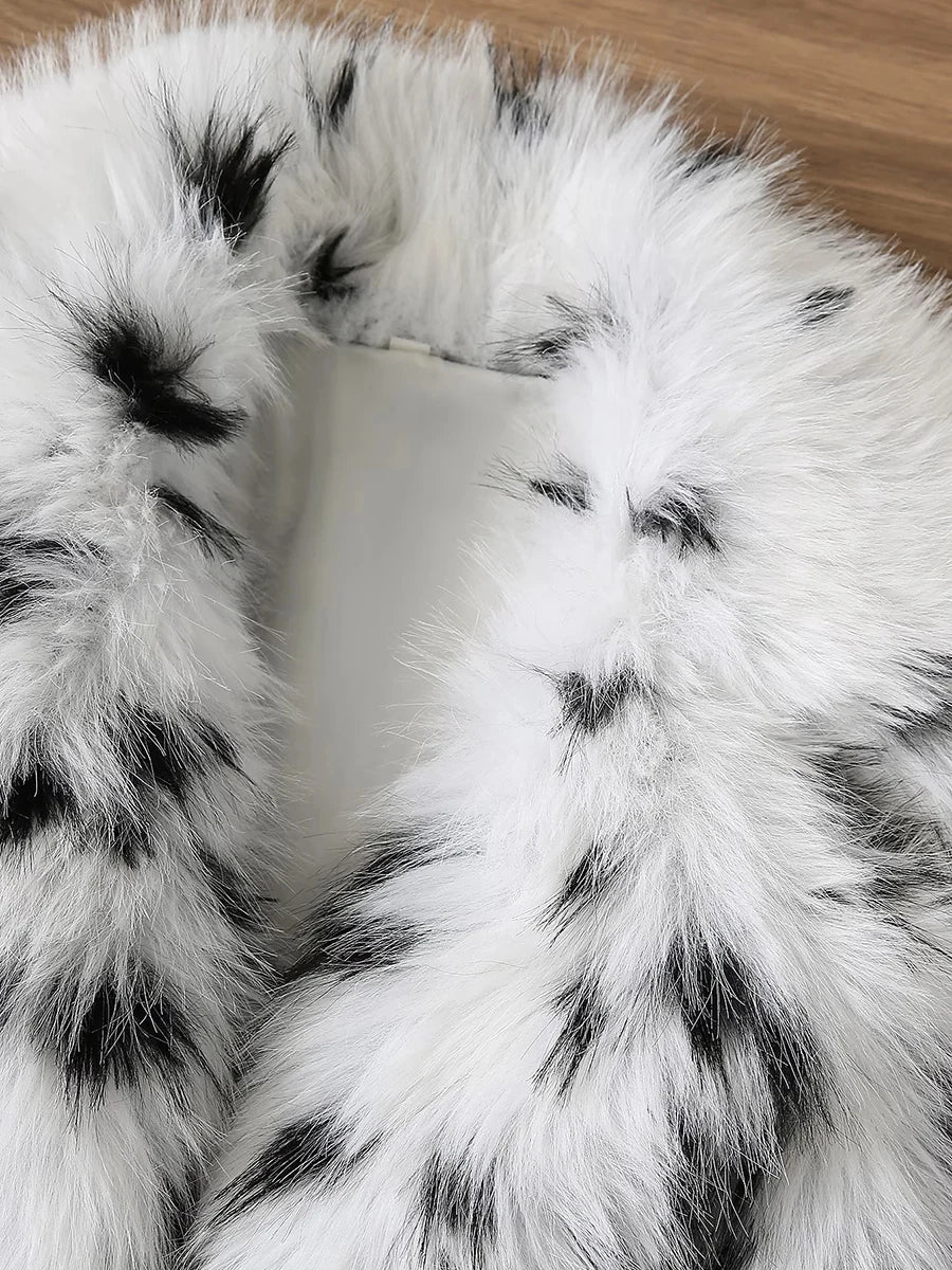 Close-up of a white fur blanket with black spots on a wooden surface