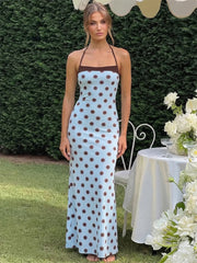 Woman in a polka dot dress standing outdoors with a table and flowers in the background