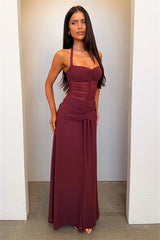 Woman wearing a burgundy dress standing against a plain wall.