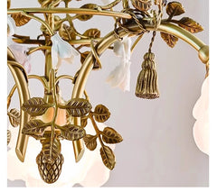 Gold chandelier with leaf designs and tassels on a light background