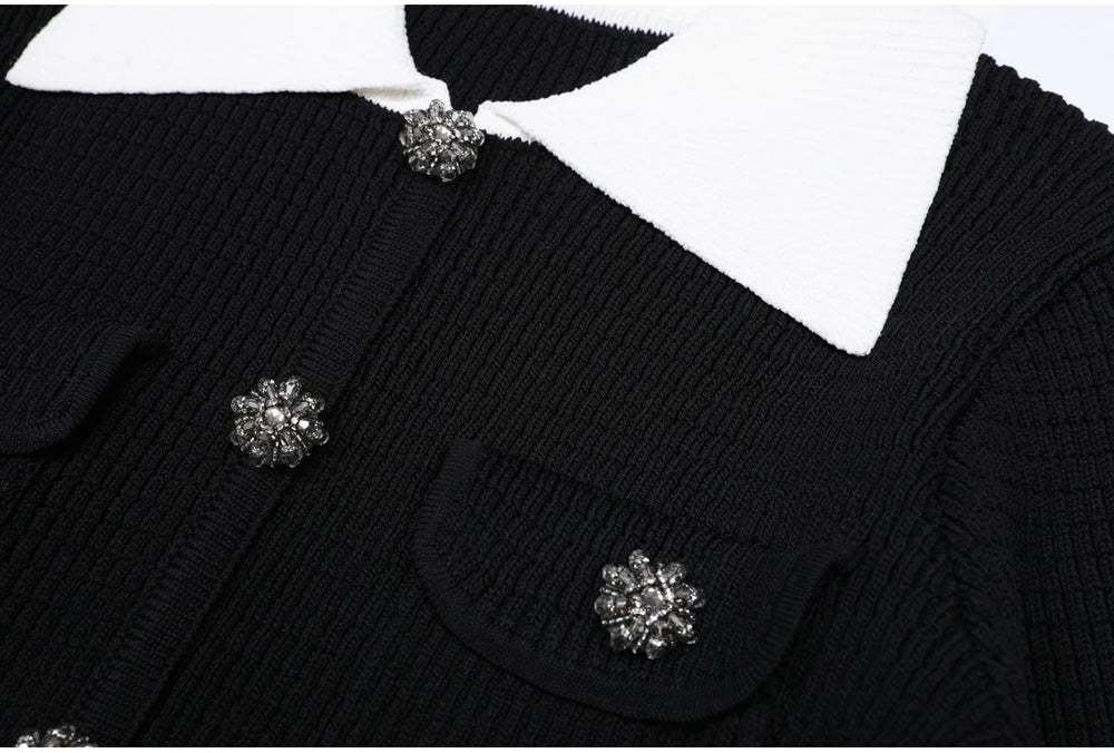 Close-up of the jeweled button and white collar detail on the black knit cardigan.