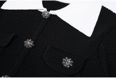 Close-up of the jeweled button and white collar detail on the black knit cardigan.
