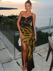 Woman in a one-shoulder dress with a tiger stripe pattern standing on a patio with ocean view.