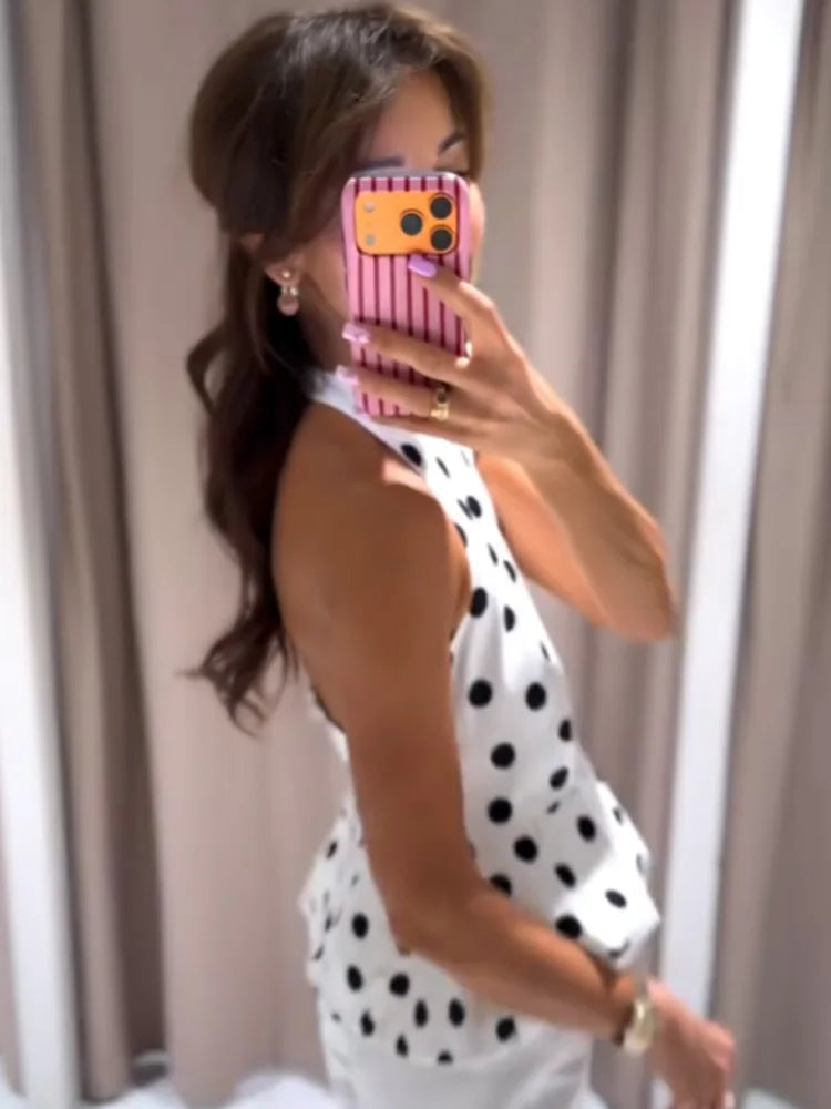 Woman taking a mirror selfie wearing a polka dot dress with a pink phone case.