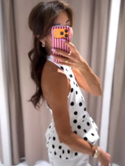 Woman taking a mirror selfie wearing a polka dot dress with a pink phone case.