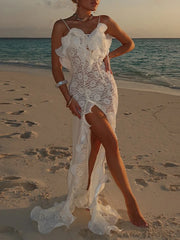 Woman in a white lace dress standing on a beach at sunset