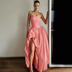 Woman wearing a pink strapless gown with a high-low hem in a room.