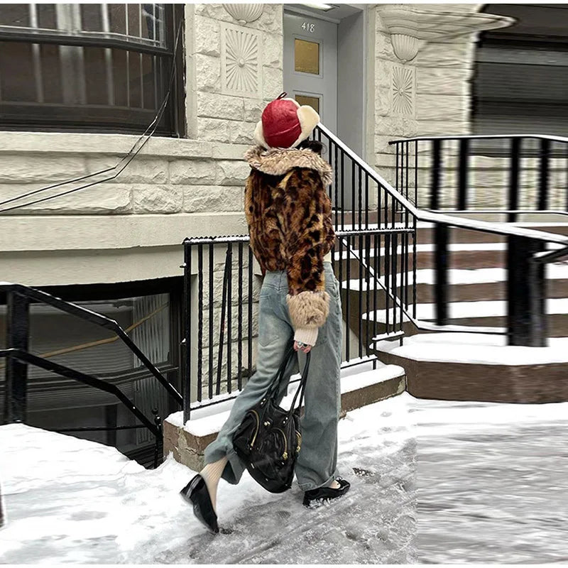 Person walking in the snow wearing a leopard print coat and red beanie with a teddy bear design.