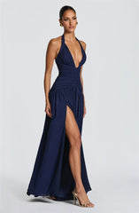 Woman wearing a deep blue evening gown with a slit on a white background