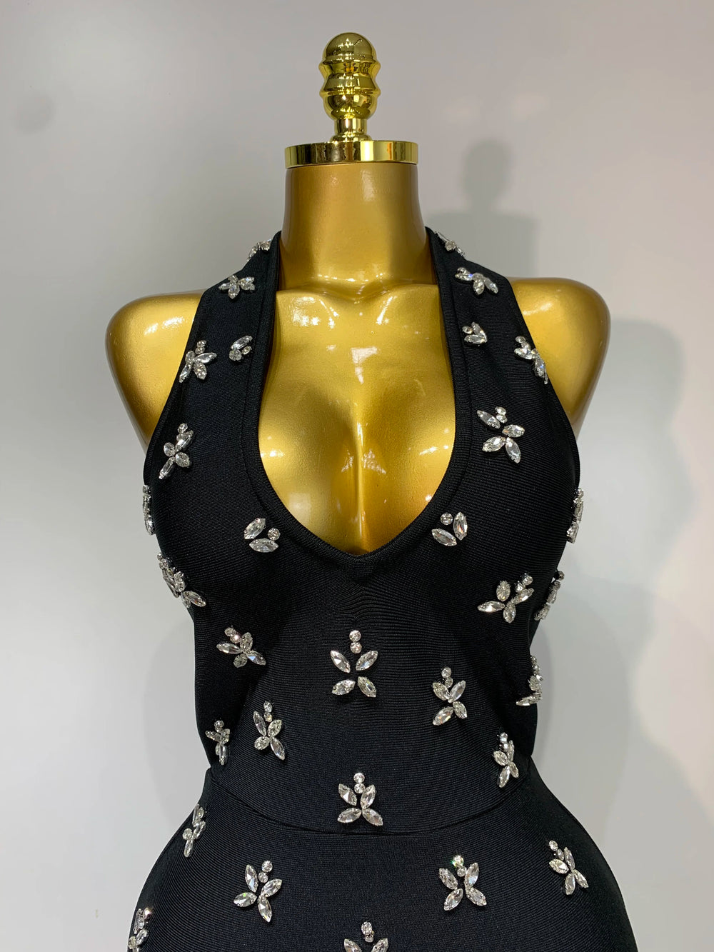 Close-up view of the halter neckline and diamond embellishments on the knit bodycon gown.