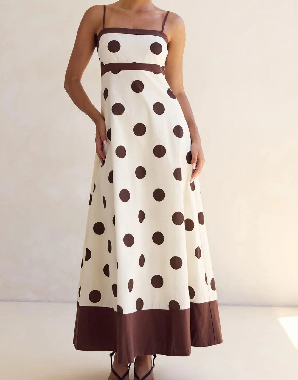 Long polka dot dress with brown accents on a plain background