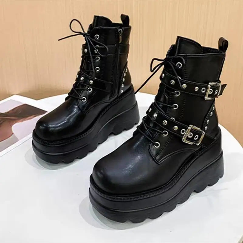 Pair of black leather boots with buckles on a white surface.