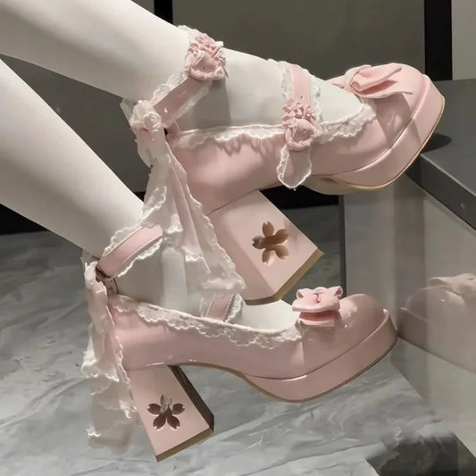 Pink high-heeled shoes with floral details worn by a person.