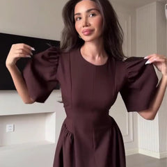 Woman wearing a burgundy dress with puffed sleeves indoors.