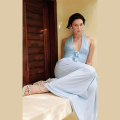 Woman in a light blue dress sitting on a couch against a beige wall.