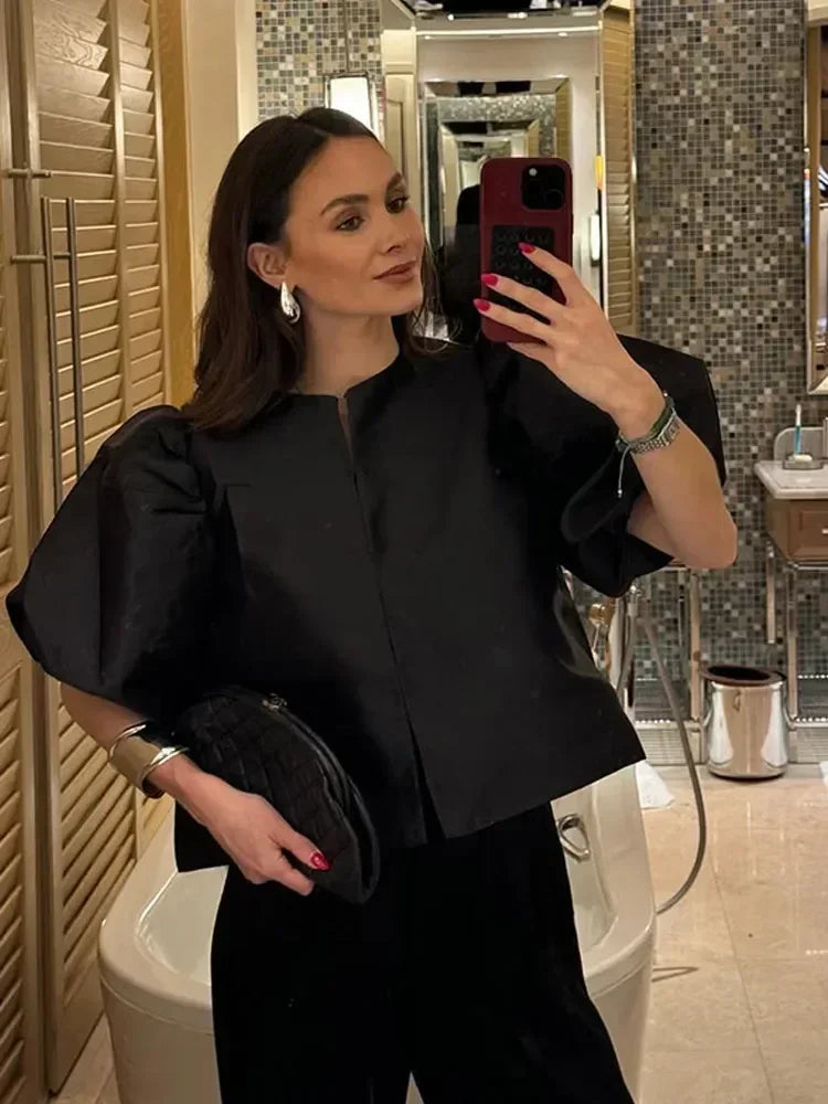 Woman taking a mirror selfie in a bathroom wearing a black outfit.