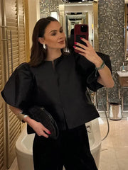Woman taking a mirror selfie in a bathroom wearing a black outfit.
