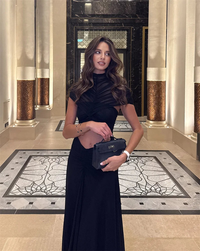 Woman in a black dress holding a handbag in an elegant interior setting
