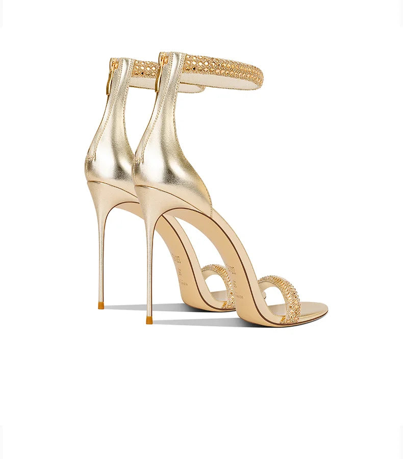 Gold high-heeled shoes with open design on a white background