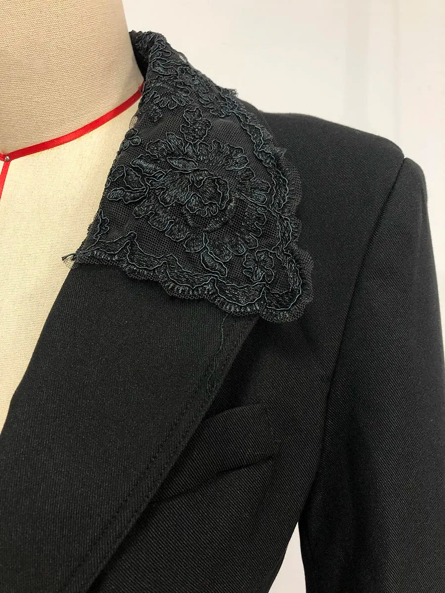 Black jacket with lace detailing on a mannequin against a neutral background