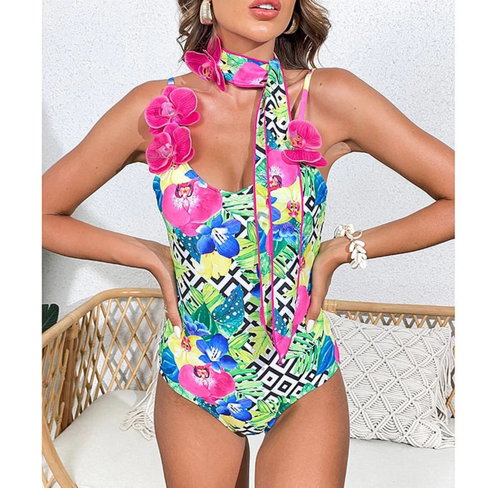 Close-up of a woman wearing a geometric and floral print one-piece swimsuit with pink orchid embellishments around the neckline