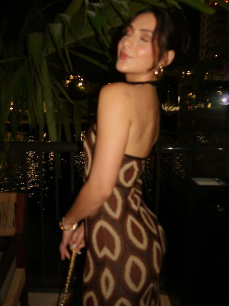 Woman in a patterned dress standing outdoors at night with city lights in the background