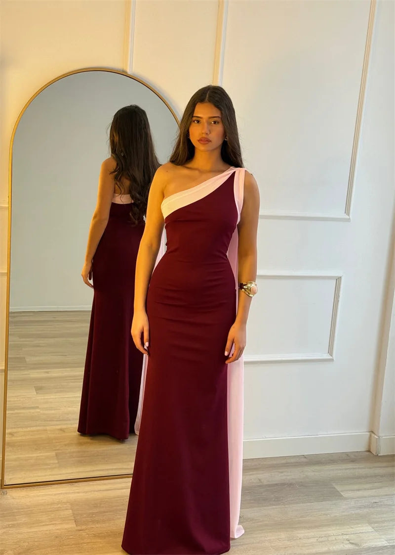 Woman wearing a burgundy and pink one-shoulder dress in front of a mirror.