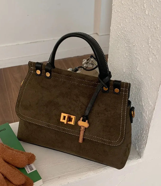 Brown handbag with gold accents on a white surface