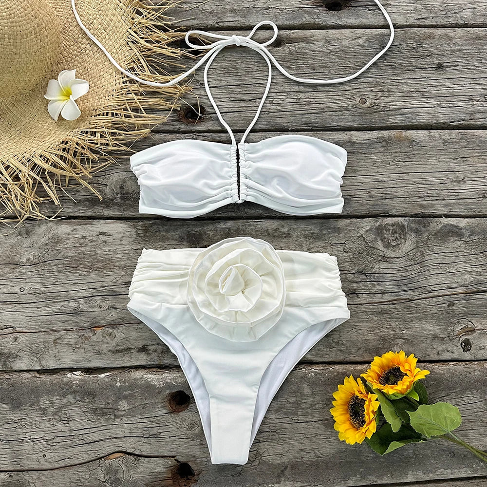 Flat lay of a white bikini set with ruched details and a rose embellishment.