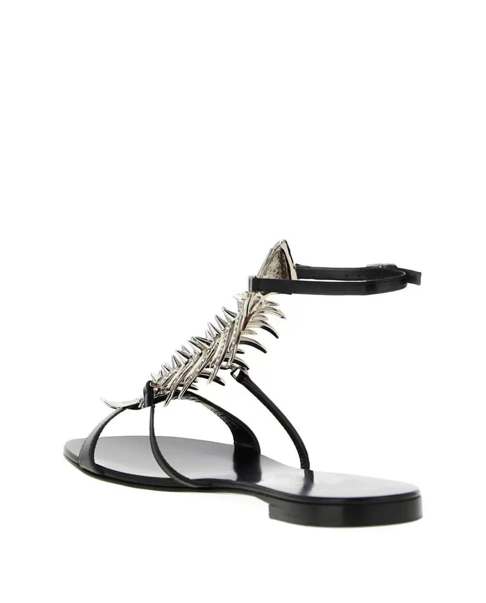 Side view of a black flat sandal with a silver rhinestone fishbone embellishment and ankle strap