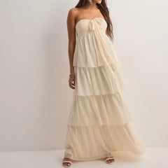 Woman wearing a strapless, tiered beige dress against a white background