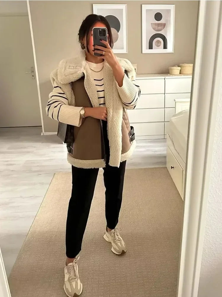 Person taking a mirror selfie wearing a stylish outfit with a jacket, pants, and sneakers in a room.
