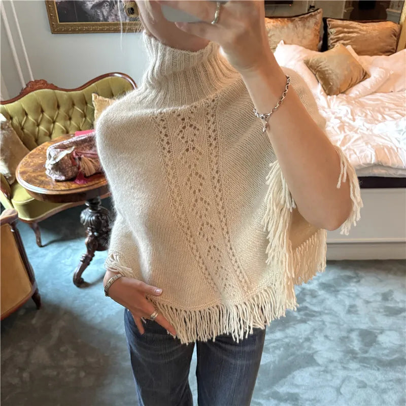 Close-up of beige knit poncho showing lace pattern and fringe