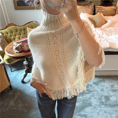 Close-up of beige knit poncho showing lace pattern and fringe