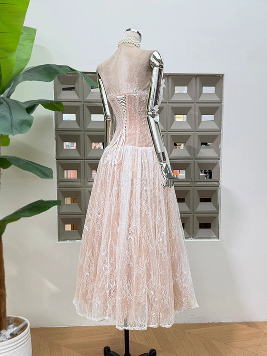 Mannequin wearing a light pink lace dress in front of a decorative wall.