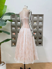 Mannequin wearing a light pink lace dress in front of a decorative wall.