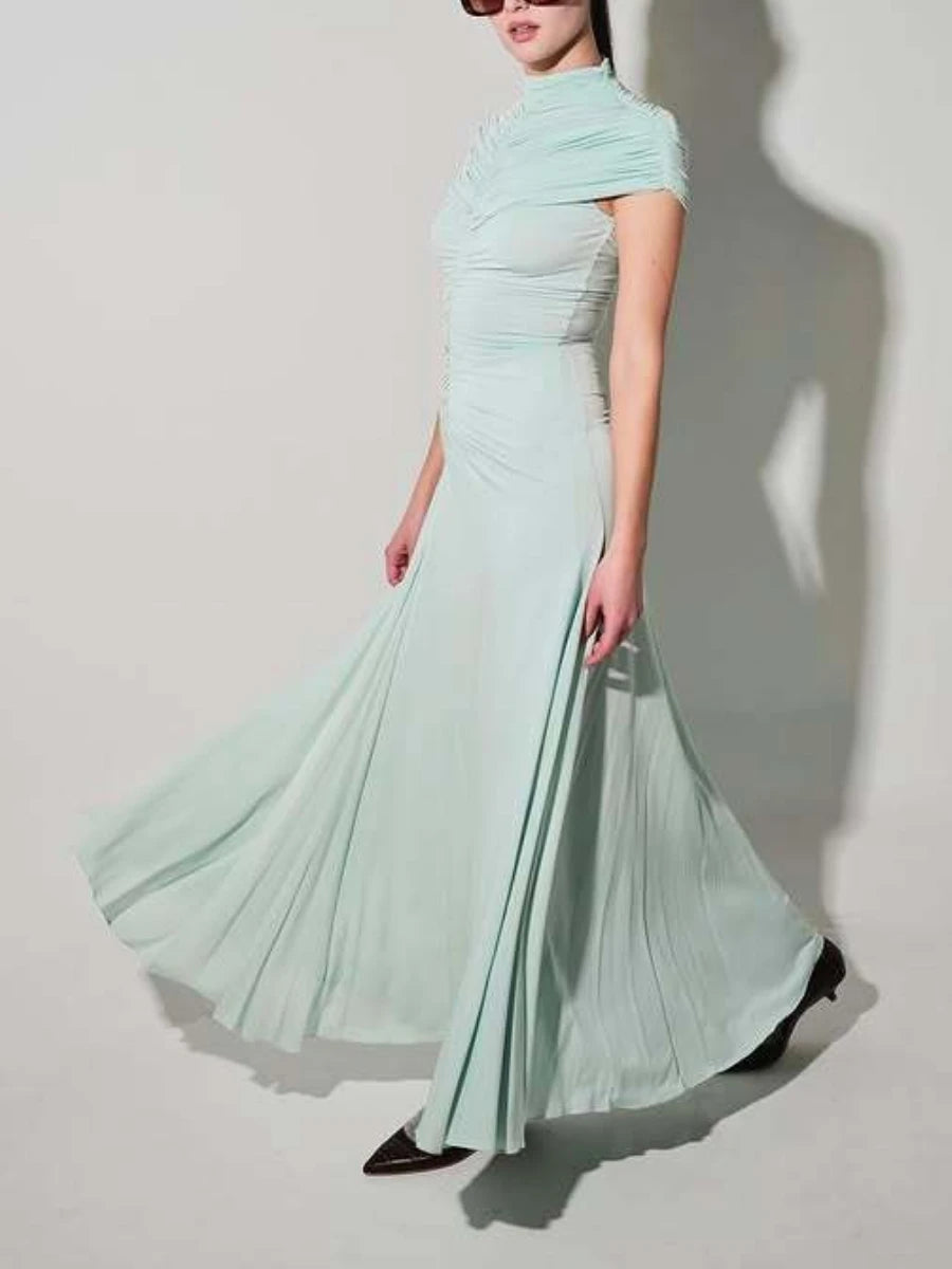 Woman wearing a light green evening gown against a plain background