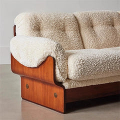 Designer wooden-frame sofa with curved armrests and cozy aesthetic
