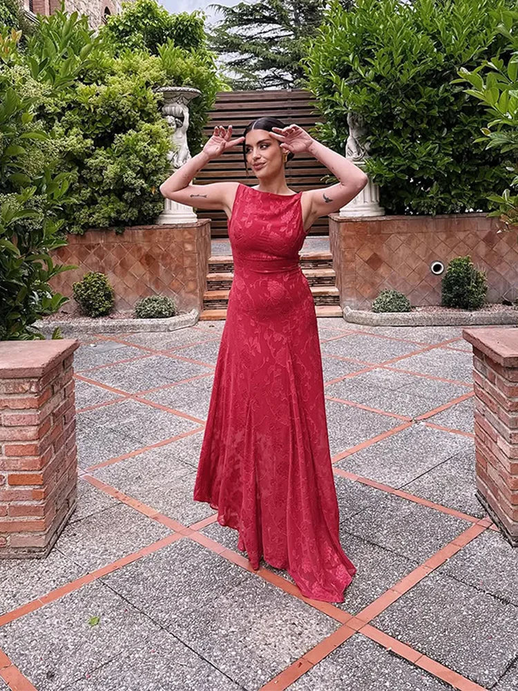 Woman in a red dress standing in an outdoor garden setting