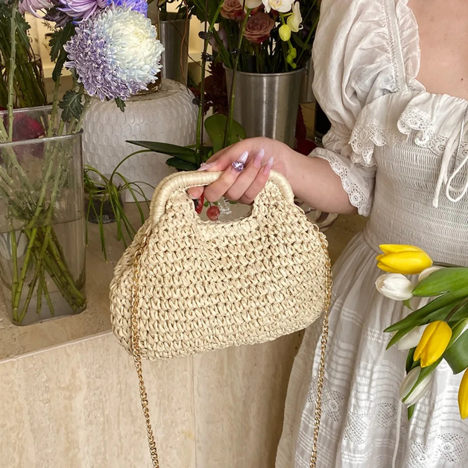 Person holding a woven handbag with flowers and a vase in the background