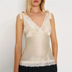 Woman wearing a beige top with lace details on a plain background