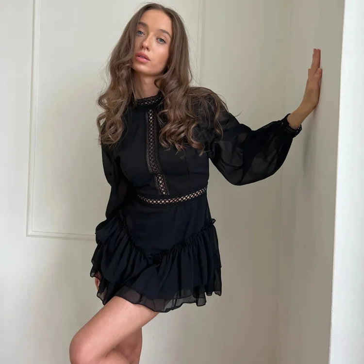 Woman wearing a black dress with long sleeves against a plain background