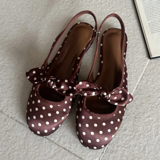 Brown polka dot slingback pumps with a bow accent.