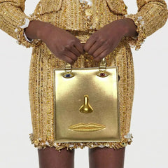 Gold sculptural face structured tote bag with top handle.