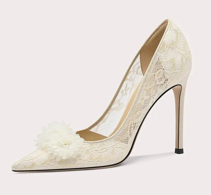White lace high-heeled shoe with decorative elements on a light gray background