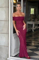 Woman in a burgundy lace dress standing in a room with checkered floor and decorative elements.
