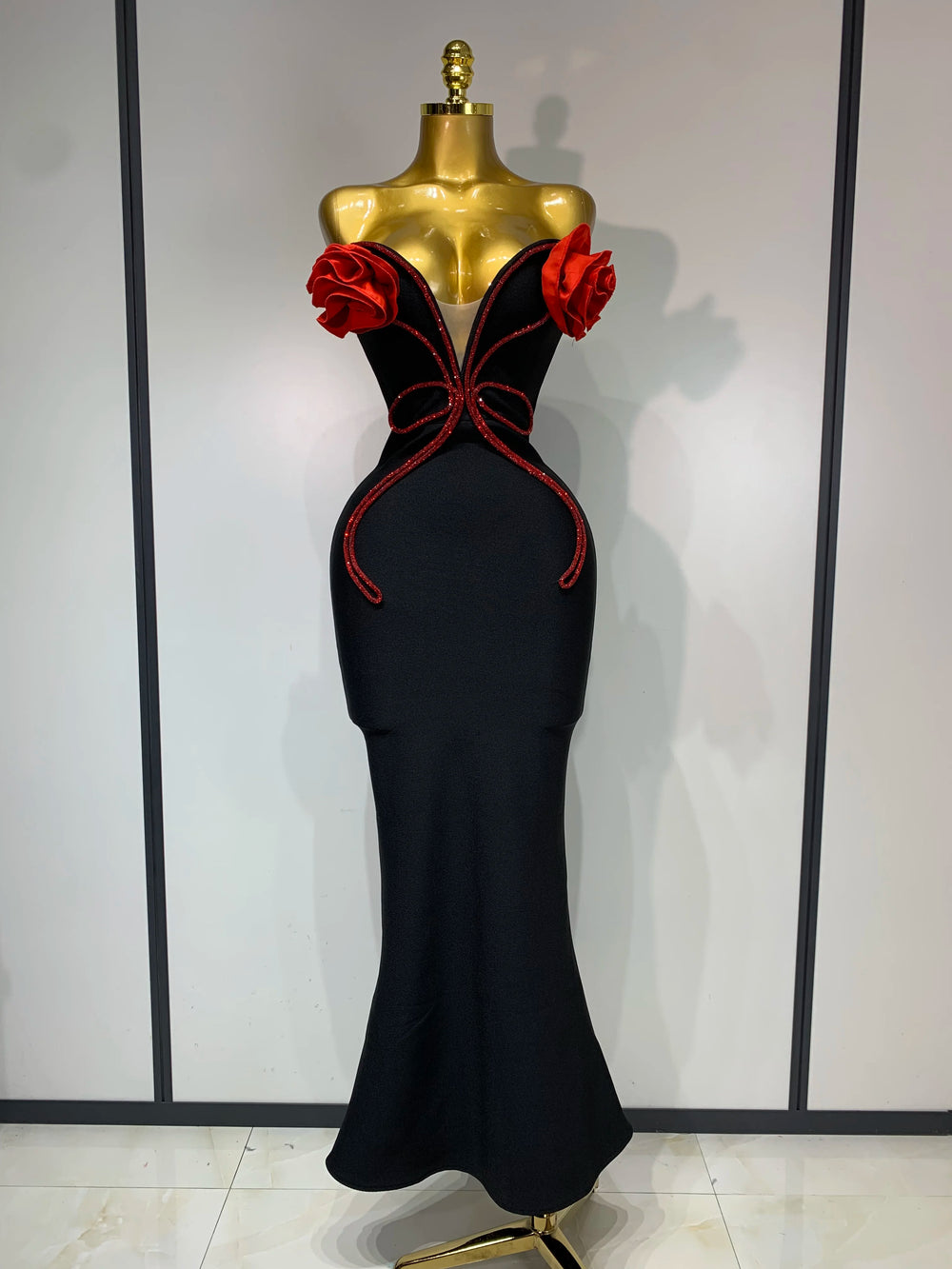 Black evening gown with red detailing on a mannequin against a plain background