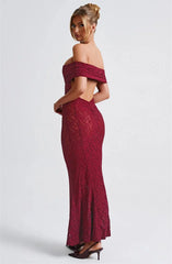 Woman wearing a burgundy off-shoulder lace dress on a white background